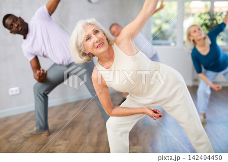 Active mature men and women practicing Jazz-funk dance in training hall Active mature men and women practicing Jazz-funk dance in training hall 142494450