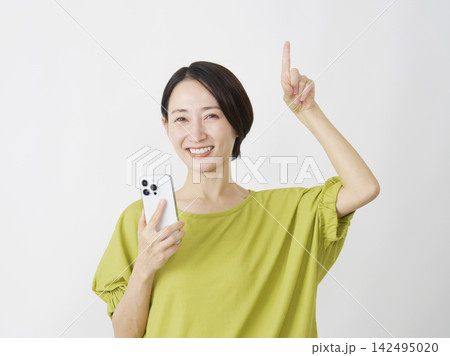 スマホを持って上を指差すミドル女性 白背景 スマホを持って上を指差すミドル女性 白背景 142495020