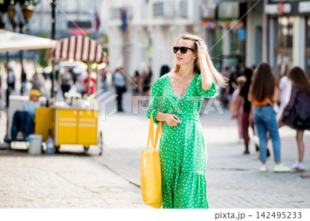 Young beautyful woman with yellow linen eco bag on city background. Young beautyful woman with yellow linen eco bag on city background. 142495233