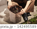 コンポストの土をかき混ぜる人 142495589