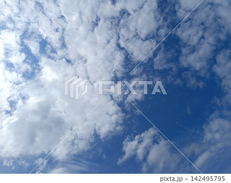 Vibrant blue sky dotted with fluffy white clouds. Fair weather daytime sky background Vibrant blue sky dotted with fluffy white clouds. Fair weather daytime sky background 142495795