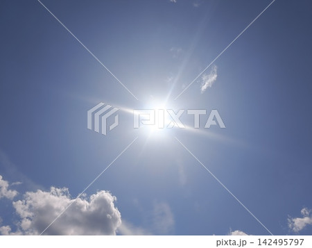Bright sun with starburst effect shining in a clear blue sky. Sunny summer day background. Copy space for text 142495797