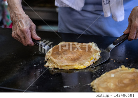 両手のへらでお好み焼きを返す熟練の技 両手のへらでお好み焼きを返す熟練の技 142496591