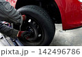 車のタイヤを外している自動車整備士の手 142496786