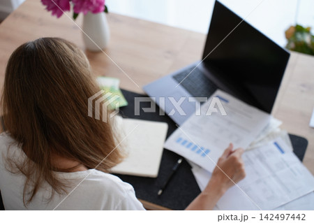 Woman reviewing bills and financial documents at home 142497442