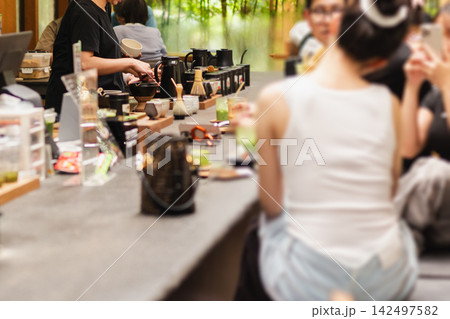 Customers sitting at counter while a barista prepares Japanese matcha green tea . 142497582