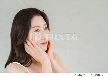 頬に手を添えて美肌を確認する大人女性のスキンケア,美容イメージ 頬に手を添えて美肌を確認する大人女性のスキンケア,美容イメージ 142498172