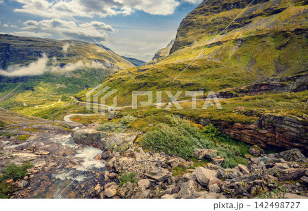 Autumn mountain landscape in Norway. Winding road in the mountains. Road 63 to Geiranger. View from Upper Blaafjeld Bridge Autumn mountain landscape in Norway. Winding road in the mountains. Road 63 to Geiranger. View from Upper Blaafjeld Bridge 142498727