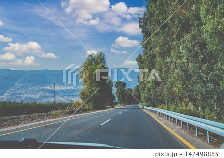 Driving a car on a mountain road. View through the windshield. Hula Valley, Israel Driving a car on a mountain road. View through the windshield. Hula Valley, Israel 142498885