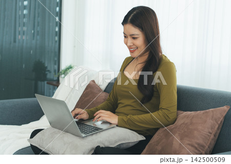 Young Asian Woman Studying Online with Laptop, Tablet, Smartphone and Headphones at Home, Adult Education and E-Learning 142500509