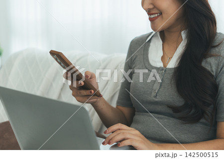 Young Asian Woman Studying Online with Laptop, Tablet, Smartphone and Headphones at Home, Adult Education and E-Learning 142500515
