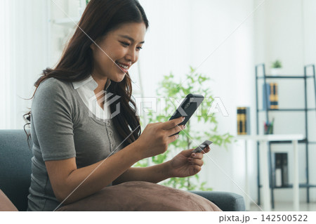 Young Asian Woman Studying Online with Laptop, Tablet, Smartphone and Headphones at Home, Adult Education and E-Learning 142500522
