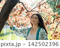 Portrait of attractive woman touching tree trunk in park near pond 142502396