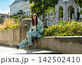 Happy adult female enjoying sunny day outdoors with historic architecture background. 142502410