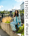 Full length vertical portrait of smiling 38 year old Armenian woman sitting on stone ledge outdoors 142502411