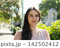 Portrait of attractive 34 year old brunette woman smiling gently in park 142502412