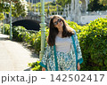 Portrait of happy brunette woman walking in sunlit park expressing femininity and confidence 142502417