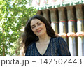 Beautiful adult Armenian woman looking directly at camera with gentle smile outdoors in sunlight 142502443