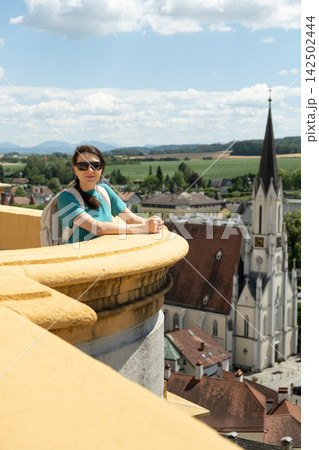 Woman tourist with backpack enjoying panorama of the old Austrian historical city. Woman tourist with backpack enjoying panorama of the old Austrian historical city. 142502444