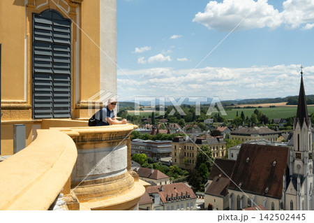 Male tourist with backpack looking down at the town from a historic balcony Male tourist with backpack looking down at the town from a historic balcony 142502445