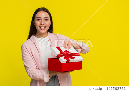 Woman opening birthday gift box with surprised happy expression joyful emotional reaction to present Woman opening birthday gift box with surprised happy expression joyful emotional reaction to present 142502731