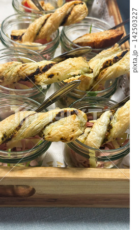 Puff pastry snacks with Ocimum basilicum pesto are served in glass jars. The scene represents hospitality, celebration and sharing. Puff pastry snacks with Ocimum basilicum pesto are served in glass jars. The scene represents hospitality, celebration and sharing. 142503227