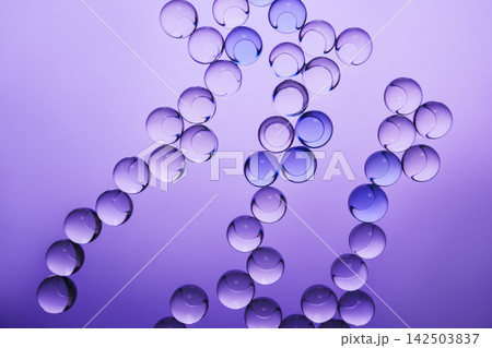 Clear and blue spheres forming an abstract chains on gradient purple surface Clear and blue spheres forming an abstract chains on gradient purple surface 142503837