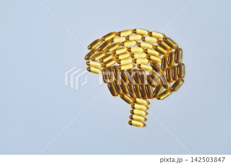 Yellow softgel omega 3 capsules forming human brain shape on light background Yellow softgel omega 3 capsules forming human brain shape on light background 142503847