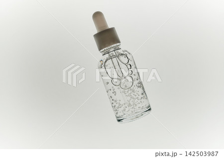 Skincare serum in glass dropper bottle with clear liquid and many bubbles Skincare serum in glass dropper bottle with clear liquid and many bubbles 142503987