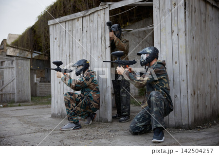 An armed group of several soldiers practice with weapons on a training field together 142504257