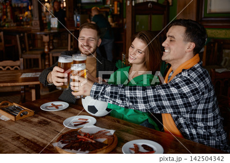 Friends celebrate sports match in lively pub ambiance with food and cheers 142504342