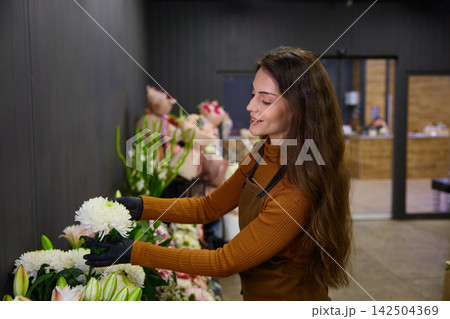 Passionate plant lover woman intricately arranges unique flower in store Passionate plant lover woman intricately arranges unique flower in store 142504369