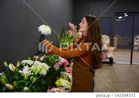 Passionate plant lover woman intricately arranges unique flower in store Passionate plant lover woman intricately arranges unique flower in store 142504371