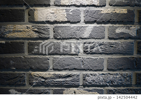 Dark grey brick wall texture background with overhead spotlight effect Dark grey brick wall texture background with overhead spotlight effect 142504442