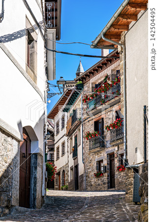 Strolling through Isaba in Roncal valley, Pyrenees, Navarre in Spain with brownish tiled roofs of residential buildings Strolling through Isaba in Roncal valley, Pyrenees, Navarre in Spain with brownish tiled roofs of residential buildings 142504495