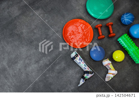 Orthoses, dumbbells, balance bars, fitness balls and rollers for physical therapy and rehabilitation classes in a modern rehabilitation center, top view Orthoses, dumbbells, balance bars, fitness balls and rollers for physical therapy and rehabilitation classes in a modern rehabilitation center, top view 142504671