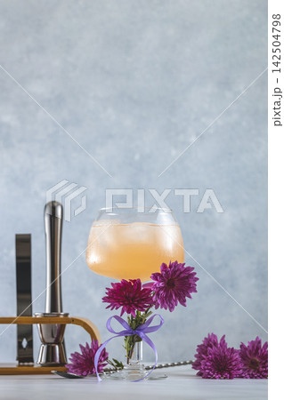 Refreshing pink cocktail decorated with flowers and bar tools in background Refreshing pink cocktail decorated with flowers and bar tools in background 142504798
