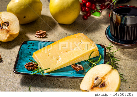Wedge of cheese with quince, walnuts and rosemary sprig on a serving plate 142505208