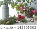 赤いキャンドルとクリスマスリース、ユーカリの緑が彩るナチュラルフローラルコーディネート 142505302