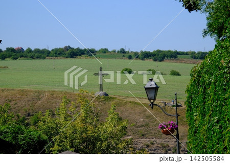 Rural Ukrainian Landscape with Green Agricultural Fields Roadside Cross Decorative Street Lamp and Flowers on Sunny Summer Day 142505584