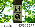 Public Toilet and Trash Bin Direction Sign Mounted on Tree Showing Restroom Symbols Arrow and Distance in Green Outdoor Park 142505587