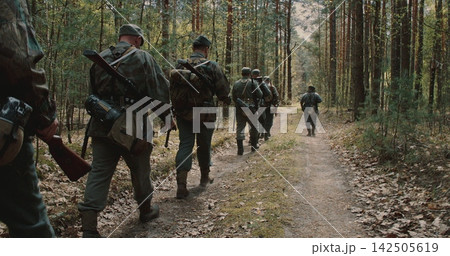 Squad of WWII German infantry soldiers marching through spring forest Squad of WWII German infantry soldiers marching through spring forest 142505619