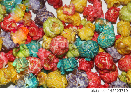 Colorful popcorn pieces in bright red, yellow, green, blue and other shades create a cheerful closeup food texture with a playful festive appearance. 142505710