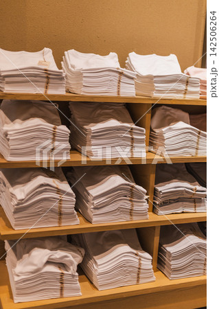 Stacks of White Folded Shirts on Wooden Shelves 142506264
