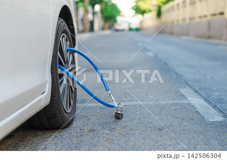White Car Wheel Secured with Blue Cable and Padlock on Bangkok Street White Car Wheel Secured with Blue Cable and Padlock on Bangkok Street 142506304
