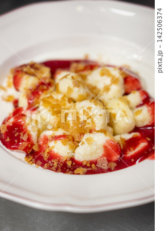Sweet gnocchi dessert. Lazy dumplings. Tasty dish served with red berry sauce topping cereal flake on white plate. Appetizing curd balls with jam. Sweet gnocchi dessert. Lazy dumplings. Tasty dish served with red berry sauce topping cereal flake on white plate. Appetizing curd balls with jam. 142506374