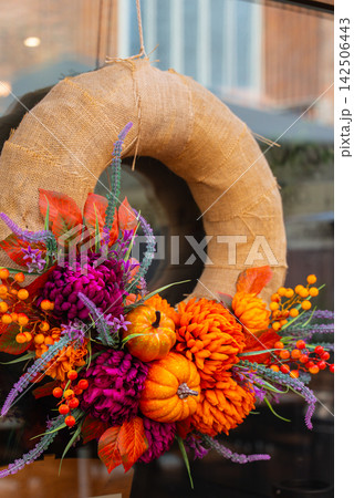 Handcrafted design of Autumn Door Wreath and ornamental details against door background. Soft natural lighting orange yellow red and brown tones emphasizing the cozy character of fall home decoration Handcrafted design of Autumn Door Wreath and ornamental details against door background. Soft natural lighting orange yellow red and brown tones emphasizing the cozy character of fall home decoration 142506443