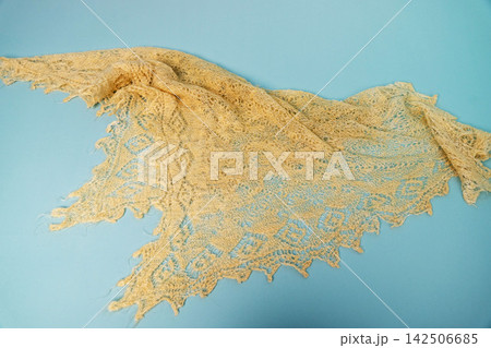 Knit lace shawl placed on a blue background to highlight its design Knit lace shawl placed on a blue background to highlight its design 142506685