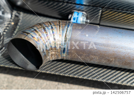 Close-up view of metal exhaust pipe with weld seams from a vehicle at a workshop Close-up view of metal exhaust pipe with weld seams from a vehicle at a workshop 142506757