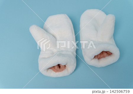 Warm white mittens with bunny ears on a light blue background Warm white mittens with bunny ears on a light blue background 142506759